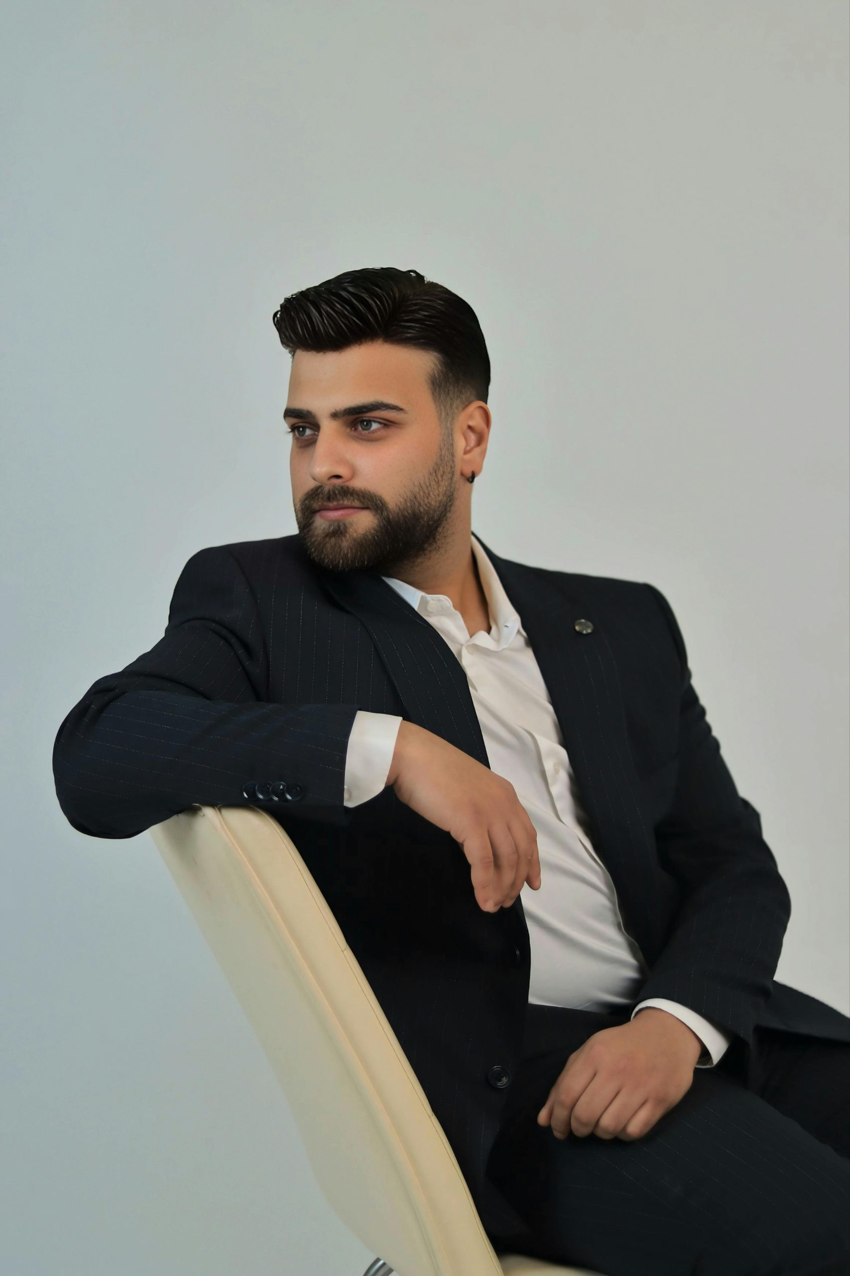 Portrait of a confident businessman in a suit sitting on a chair with a thoughtful expression.